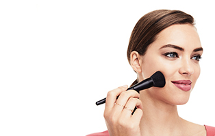 Woman with Mary Kay Powder Foundation Brush representing the variety of finishes and coverage options available in the Foundation Guide.