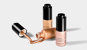 Three bottles of Mary Kay Illuminating Drops are shown with one tipped over and product spilling out. 