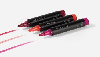 Three Mary Kay Lip Tints are shown with streaks of color drawn out in front of them.